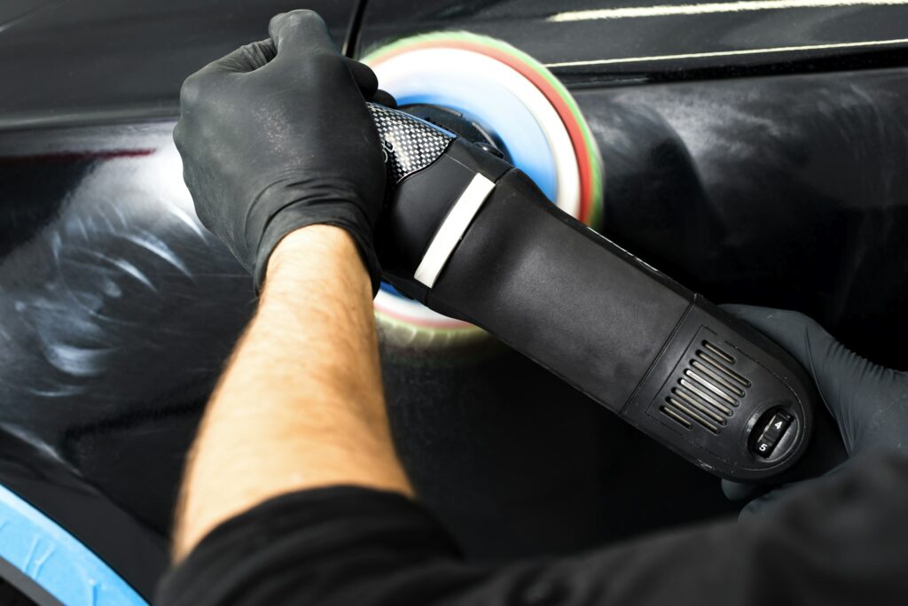 Buffing and polishing car. Car detailing. Man holds a polisher in the hand and polishes the car