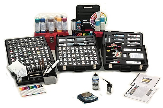 A comprehensive artist kit featuring a variety of paints, brushes, a color wheel, spray colors, and a notebook arranged in multiple cases and containers—reminiscent of the organization skills learned from PDR Training in California.