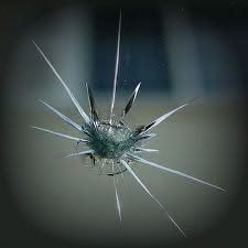 Close-up image of a shattered glass surface with radial cracks emanating from a central impact point, reminiscent of the precision required in PDR Training in California.