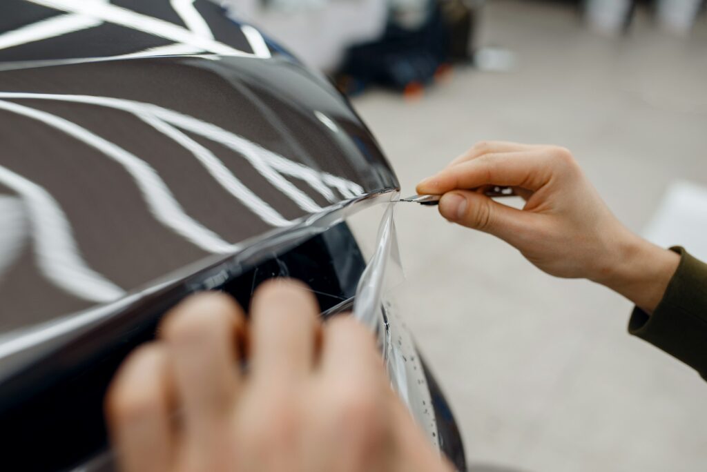 Worker installs protection film on car hood