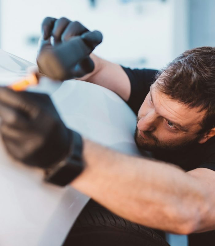 Car mechanic working to remove dent in workshop.