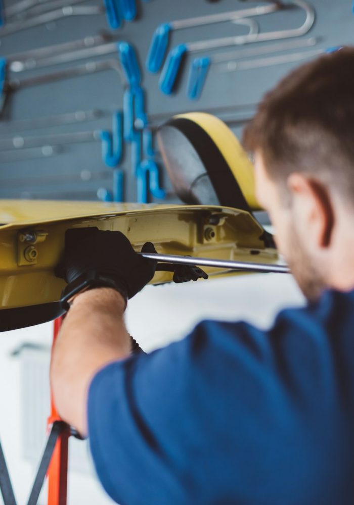 Car mechanic working to remove dent in workshop.